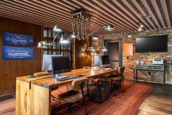 Una oficina moderna con escritorio de madera, múltiples monitores y pared de ladrillo.