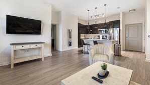 A modern kitchen with dark cabinets, stainless steel appliances, and pendant lighting. - Landing | Modern 1BD, Gym, Game Room (Fort Worth)