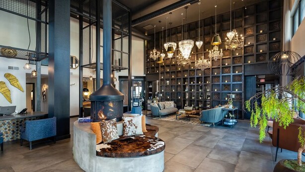 A spacious lobby with a central seating area, a fireplace, and a large wall of patterned shelves. - Landing | Modern 1BD, Gym, Game Room (Fort Worth)