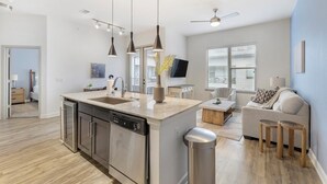 Una cocina moderna con una isla central, electrodomésticos de acero inoxidable e iluminación colgante.
