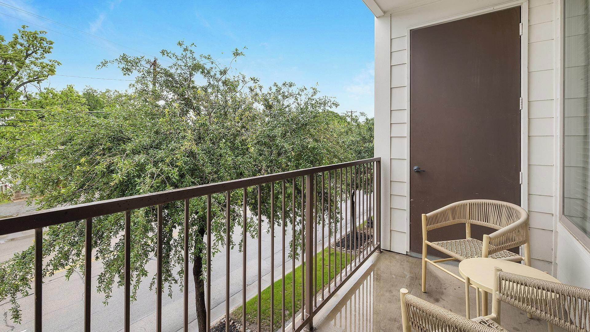 A balcony with a metal railing, wicker furniture, and a door.