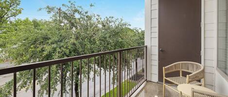 A balcony with a metal railing, wicker furniture, and a door.