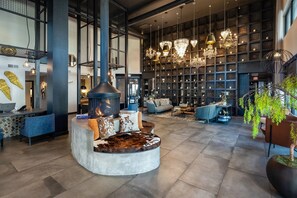 A spacious lobby with a central seating area, a fireplace, and a large wall of patterned shelves. - Landing | Incredible 2BD, Game Room, Gym (Fort Worth)