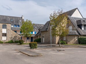 A parking lot with a stone building, a tree, and a lamppost. - Village de Légenèse by Interhome (Carnac)