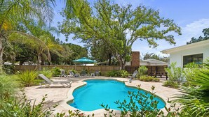 Um quintal com piscina, cercado por vegetação e cerca de madeira.
