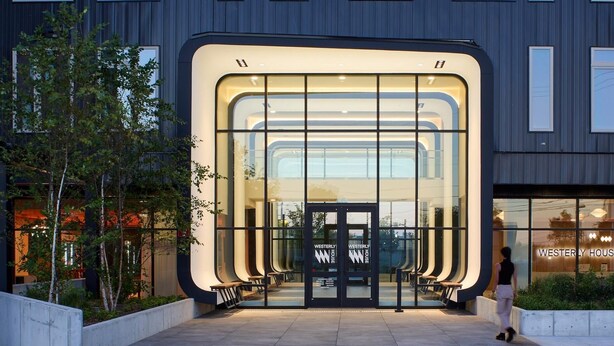 Un edificio moderno con una entrada curva, puertas de cristal y un cartel que dice 'WESTERLY HOUSE'.