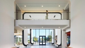 Un edificio moderno con fachada de vidrio, una escalera y una persona caminando.