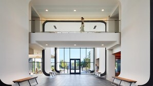 A modern building with a glass facade, a staircase, and a person walking. - Landing | Stylish Studio, Gym (Nashville)