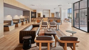 A modern hotel lobby with seating areas, a reception desk, and large windows. - Landing | Stylish Studio, Gym (Nashville)