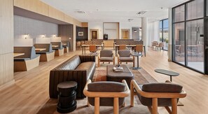 Eine moderne Hotelhalle mit Sitzbereichen, einer Rezeption und großen Fenstern.