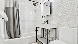 Uma casa de banho moderna com banheira, chuveiro e sanita.