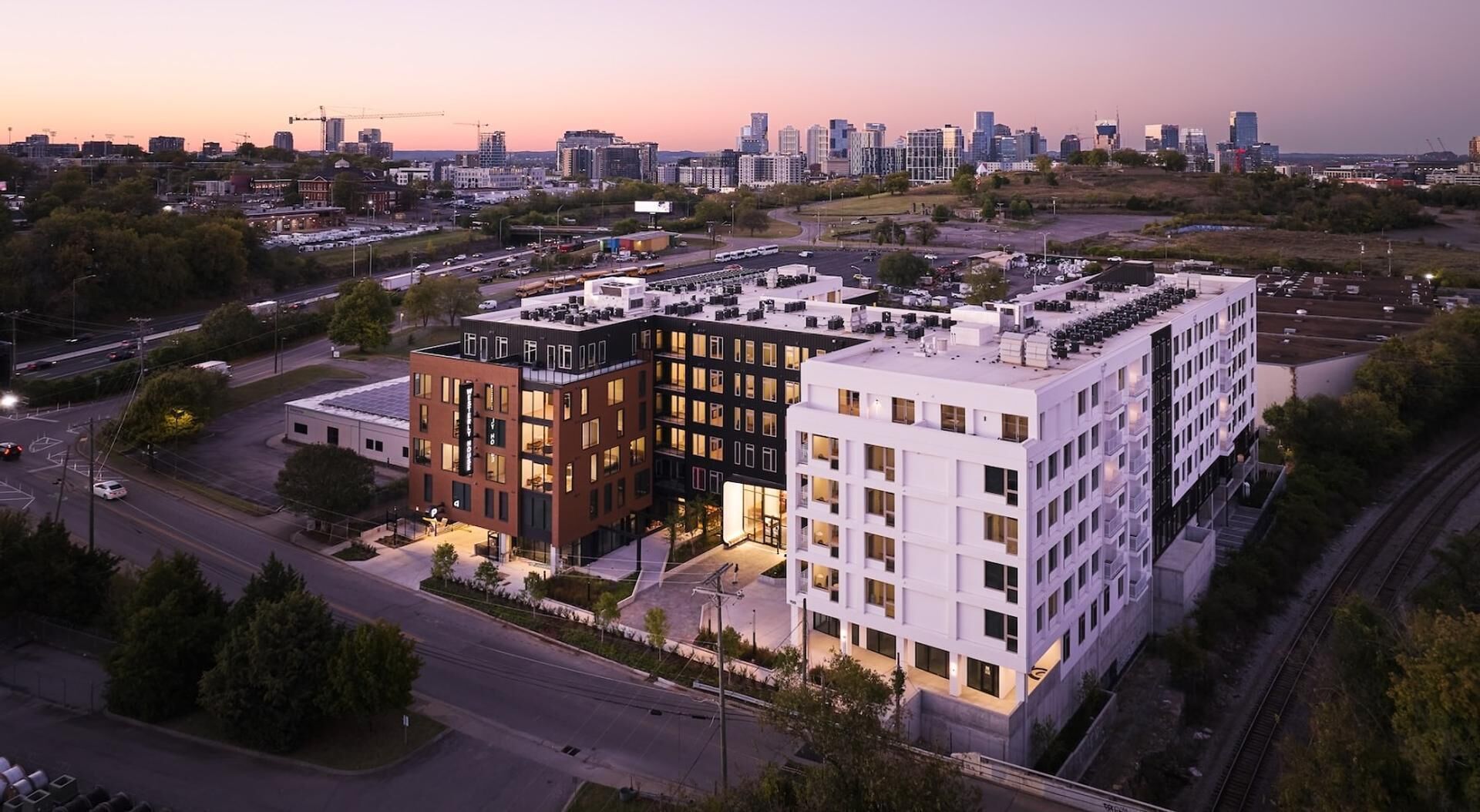 A modern building with a flat roof, large windows, and a parking lot.