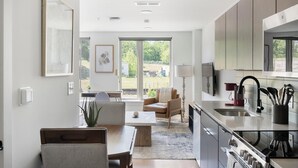 Una cucina moderna con forno integrato, un'area pranzo con tavolo e sedie e un'ampia finestra con vista sull'esterno.