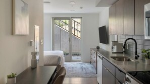 Eine moderne Küche mit Edelstahlgeräten, ein Essbereich mit einer Bank sowie eine große Schiebeglasdoor zum Balkon.