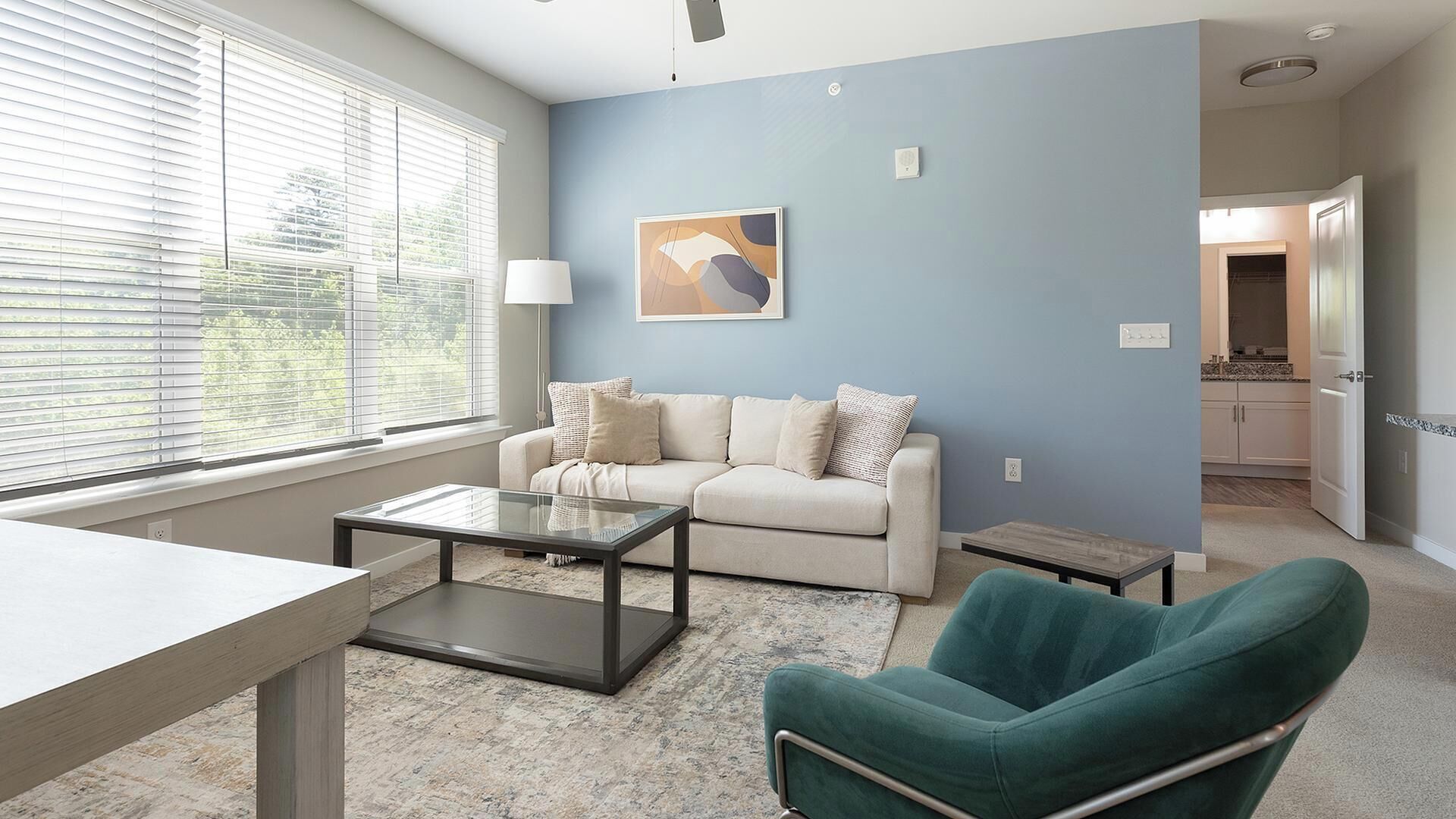 A living room with a sofa, a coffee table, and a teal armchair.