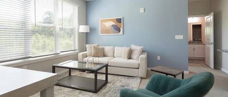 A living room with a sofa, a coffee table, and a teal armchair.