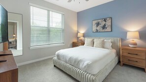 Een slaapkamer met een groot bed, nachtkastjes, een spiegel en een raam met zonwering.