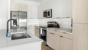 Een moderne keuken met roestvrijstalen apparatuur, een ingebouwde oven en een magnetron.