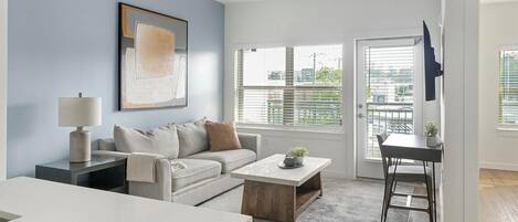A modern living room with a sofa, coffee table, and a TV on a stand.