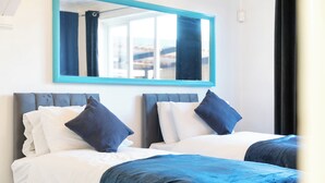 A hotel room with two beds, a large mirror, and a view of the outside.