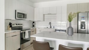 Una cocina moderna con una isla central, electrodomésticos de acero inoxidable y un jarrón con plantas.