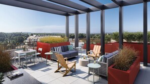 Terraza en la azotea con vistas a la ciudad, que incluye un sofá, sillas y una mesa.