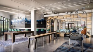 Un moderno salón de estar con mesas de billar, sofás y una mesa de futbolín.