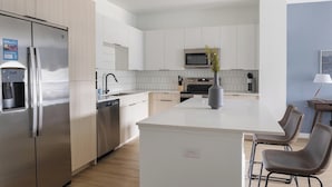 Een moderne keuken met roestvrijstalen apparatuur, witte kasten en een centraal eiland met zitplaatsen.