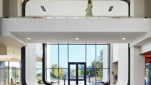 Een modern gebouw met een glazen gevel, een trap en een persoon die loopt.