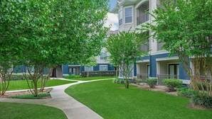 A residential building with a well-maintained lawn, a curved pathway, and a balcony. - Landing | Stunning 2BD, Clubhouse (League City)