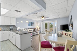 Eine moderne Küche mit weißen Schränken, einer zentralen Kochinsel, Pendelleuchten und einem Deckenventilator.