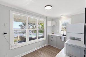 Eine moderne Küche mit großem Fenster, einem eingebauten Backofen und Blick auf eine Whirlpool-Badewanne.