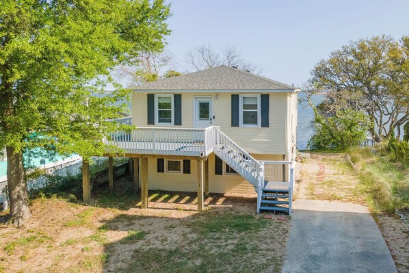 A single-story house with a covered porch and a staircase leading to a deck. - Relax on the Sunset Sound-Hot Tub Soaks & Fire Pit Nights in Kill Devil Hills (Kill Devil Hills)