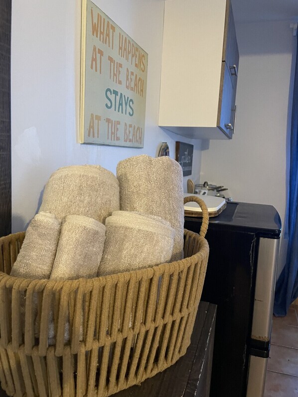 A kitchen area with a woven basket containing rolled towels, a wall sign with text, and a stove.