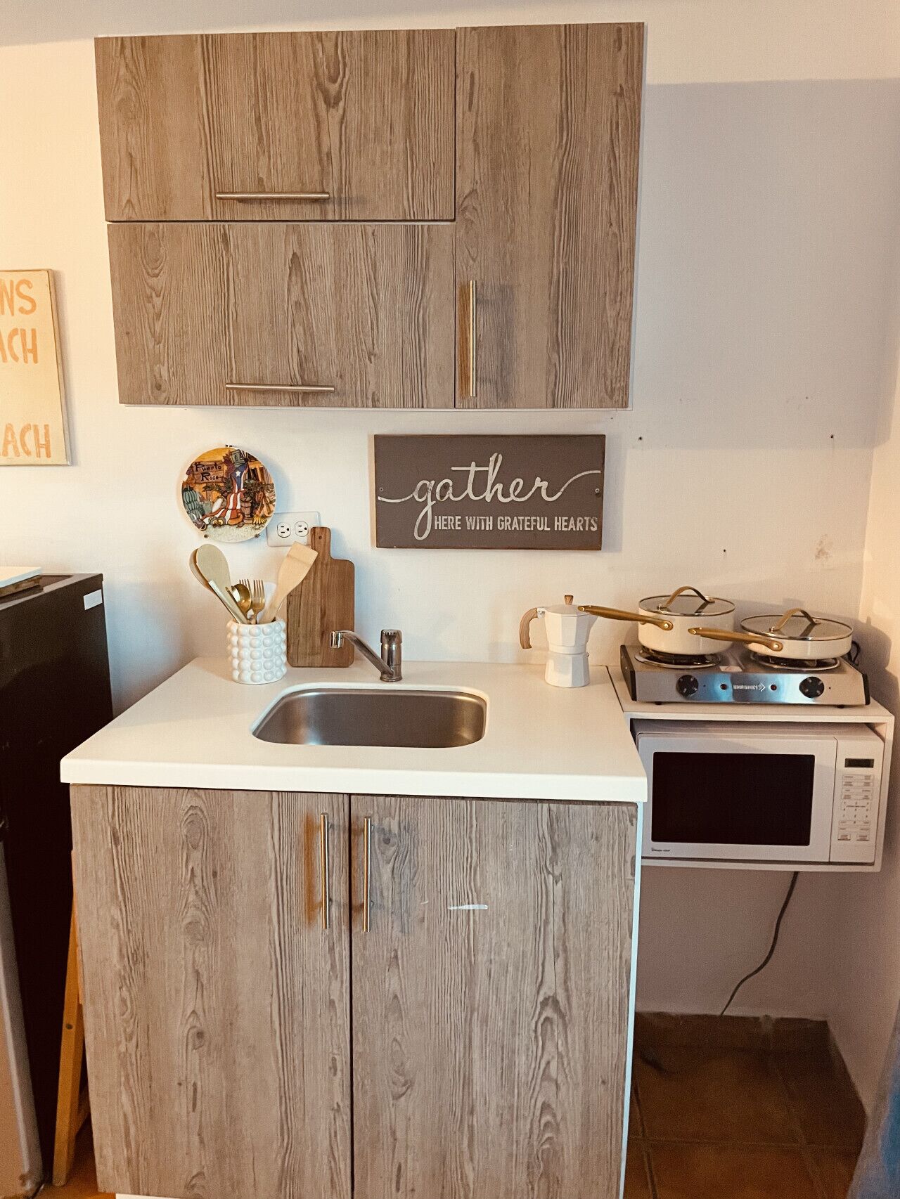 A compact kitchen with wooden cabinets, a white countertop, a sink, a stove, and a microwave.