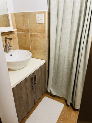 Een badkamer met een witte wastafel, houten kastjes, een handdoekhouder en een douchegordijn.