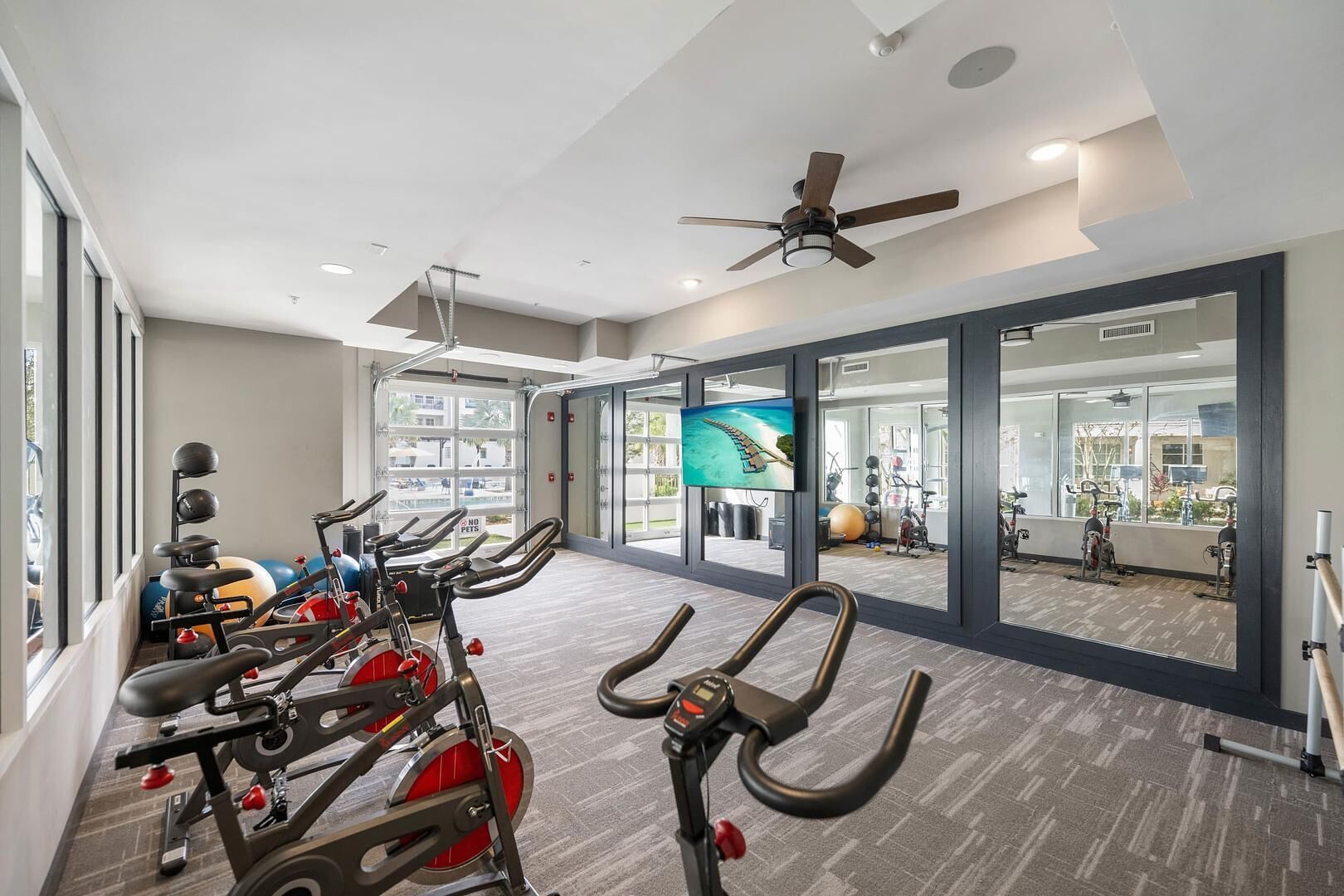 Un gimnasio con bicicletas estáticas, una cinta de correr y pelotas de ejercicio.