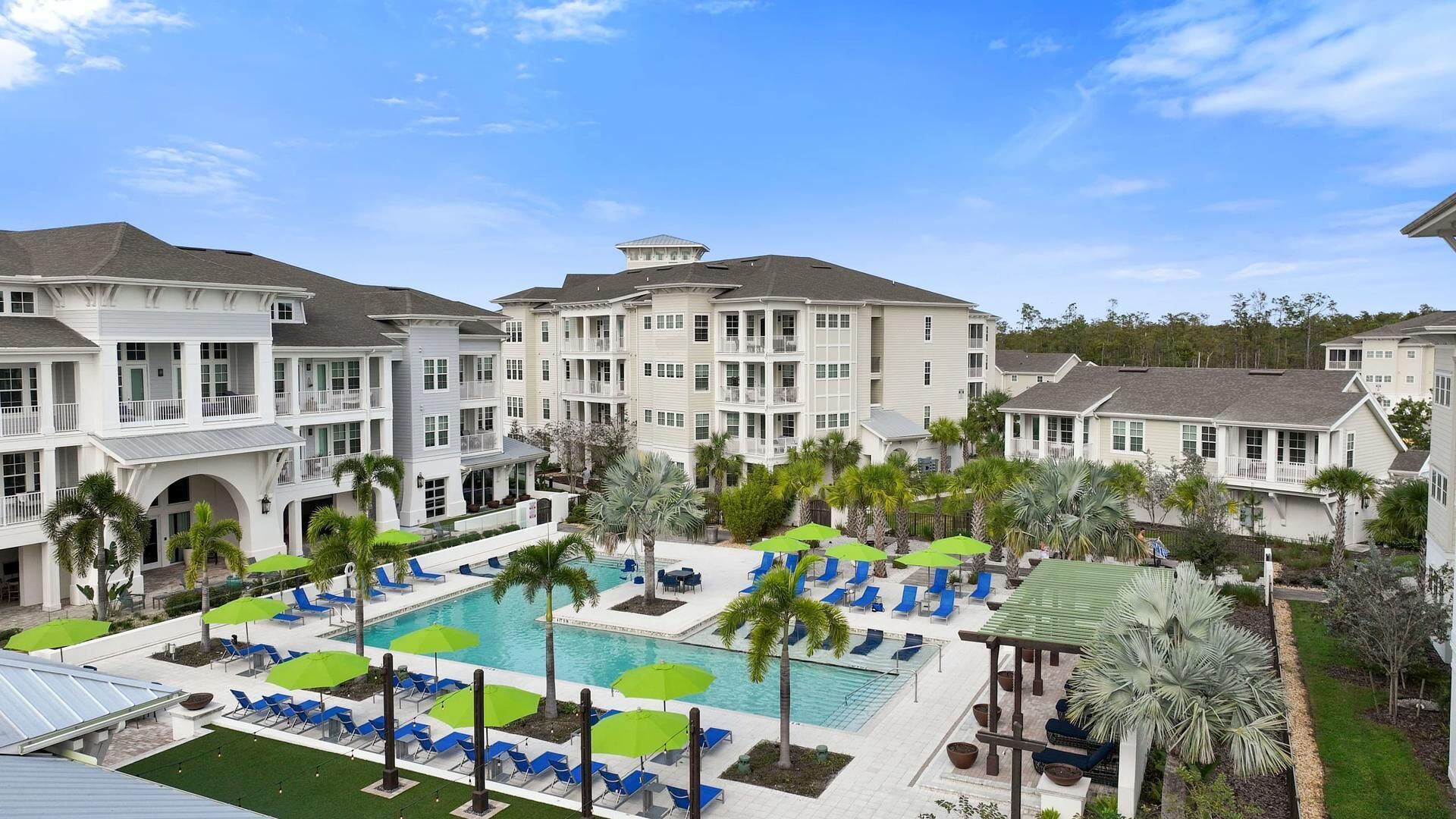 A resort with multiple-story buildings, a central swimming pool, and outdoor seating areas.