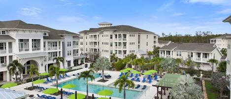 A resort with multiple-story buildings, a central swimming pool, and outdoor seating areas.