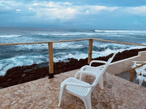 Een terras met witte plastic stoelen met uitzicht op de oceaan.