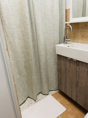 Een badkamer met een wit wastafelmeubel, een houten kast en een groen douchegordijn.