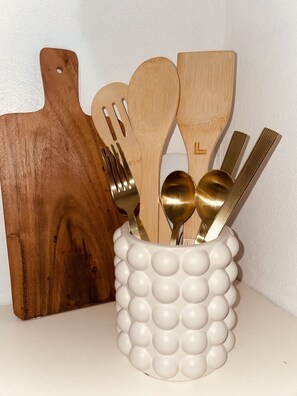 A set of wooden kitchen utensils and a white, textured container with a bubble design.