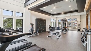 Un gimnasio con cintas de correr, máquinas de pesas y una pared de escalada.