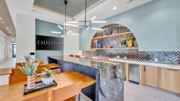 Una cocina moderna con una isla central, un letrero que dice 'CALIZA RIDGE' y un salpicadero con motivo de espiga.