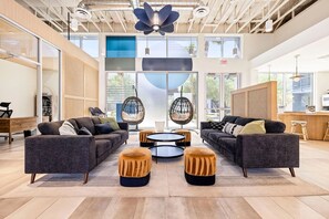 A spacious lounge area with two sofas, a round coffee table, and two hanging chairs. - Landing | Chic 2BD, Pool, Gym (Glendale)