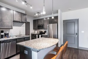 A modern kitchen with stainless steel appliances, granite countertops, and a bar area with seating. - Landing | Beautiful 2BD, Clubhouse, Gym (Louisville)