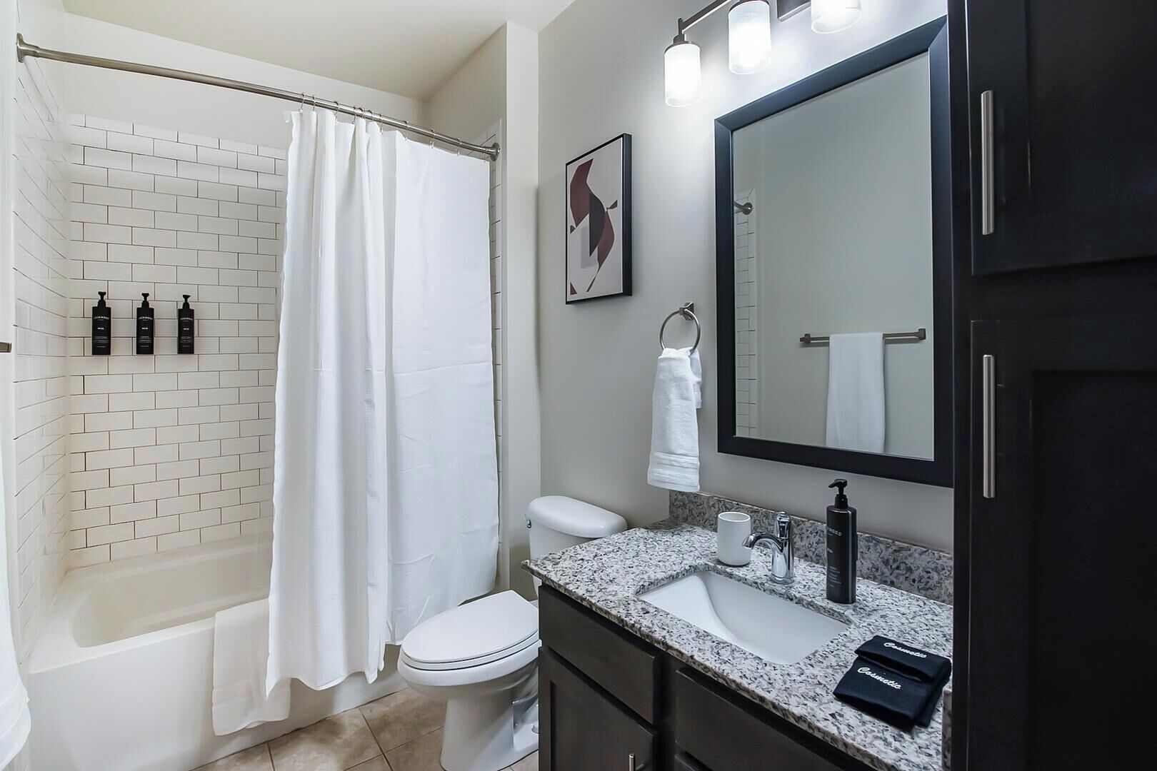 A bathroom with a shower, toilet, sink, and mirror.