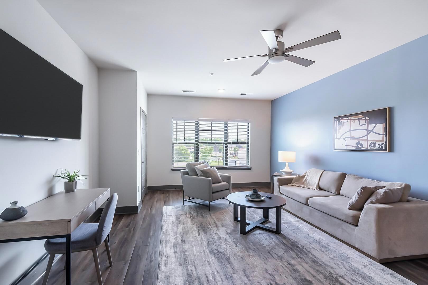 A modern living room with a ceiling fan, a sofa, a chair, a coffee table, and a TV.