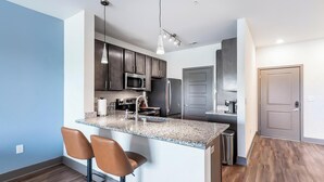 Una cocina moderna con encimeras de granito, electrodomésticos de acero inoxidable y una zona de bar con taburetes.