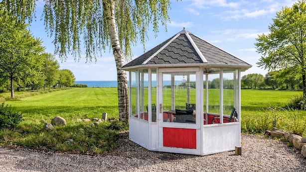 Ein Pavillon mit Glaseinfassung, rotem Unterteil und Kiesgrund.